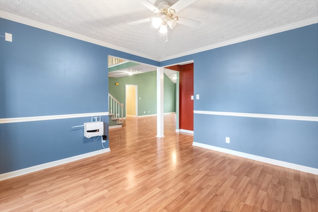 empty room with light hardwood / wood-style floors, a textured ceiling, and ornamental molding