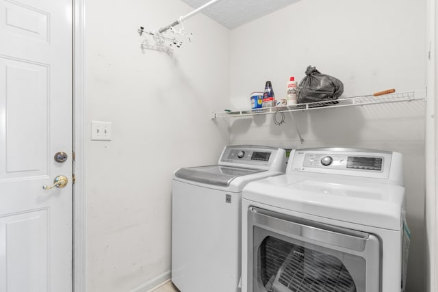 laundry room with a textured ceiling and washing machine and clothes dryer