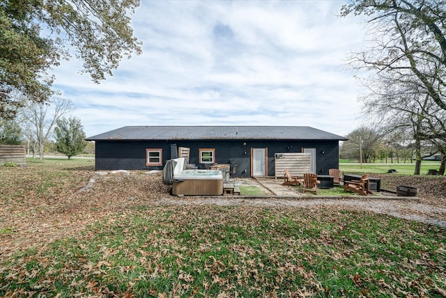 back of property featuring a hot tub, a yard, and a patio area