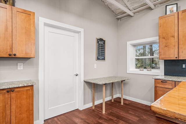 kitchen with beamed ceiling, dark hardwood / wood-style floors, and light stone counters