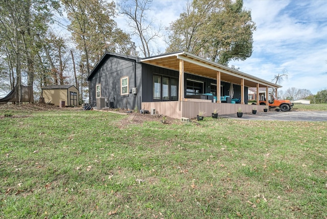 view of side of property with a lawn, cooling unit, and a storage shed