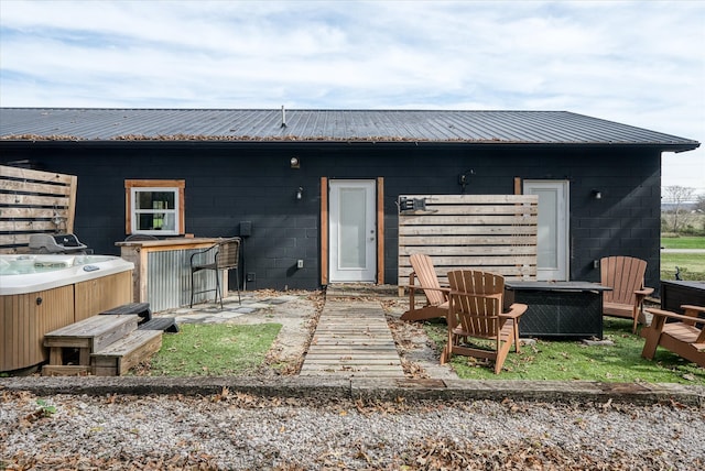 rear view of property featuring a hot tub