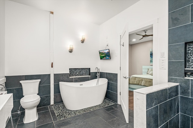 bathroom featuring a bathing tub, tile walls, and toilet