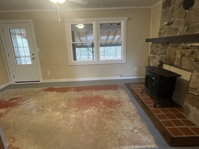 unfurnished living room featuring ceiling fan, a wood stove, and ornamental molding