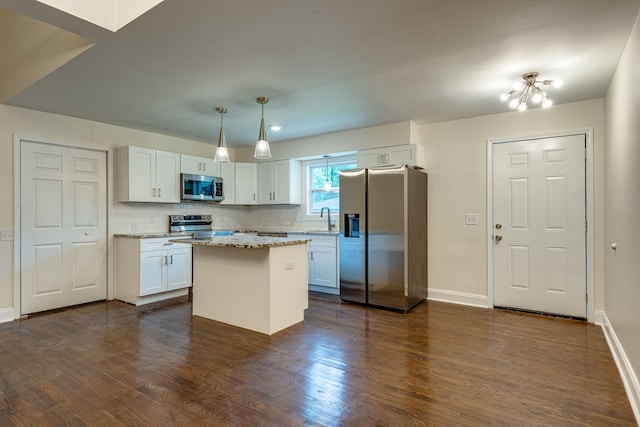 kitchen featuring stainless steel appliances, white cabinets, decorative light fixtures, and a kitchen island