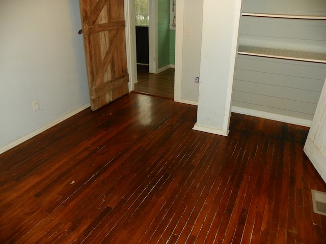 unfurnished bedroom featuring a closet and dark hardwood / wood-style flooring