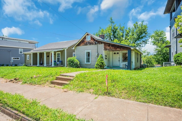 view of front of house with a front yard, central AC, and covered porch