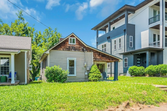 rear view of house featuring a balcony, a lawn, and central AC unit