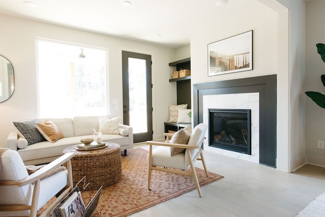 living area with a high end fireplace and light wood-style flooring