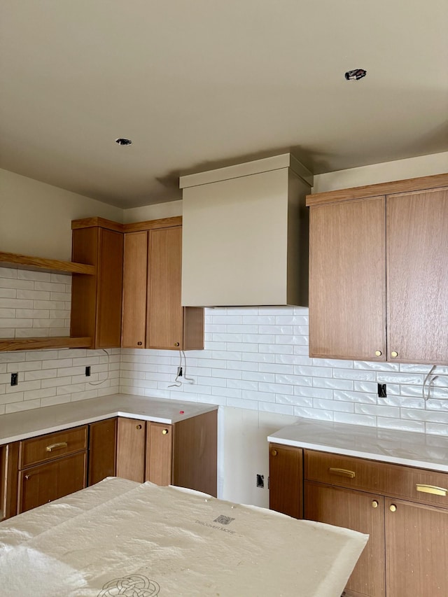 kitchen featuring brown cabinets, light countertops, and backsplash