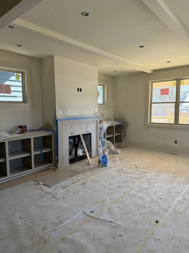 unfurnished living room with a wealth of natural light and a glass covered fireplace