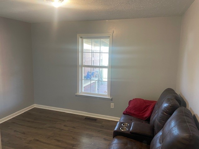 unfurnished room with a textured ceiling and dark hardwood / wood-style floors