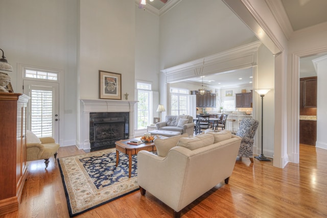 living room with a high ceiling, light hardwood / wood-style floors, a tile fireplace, and a wealth of natural light