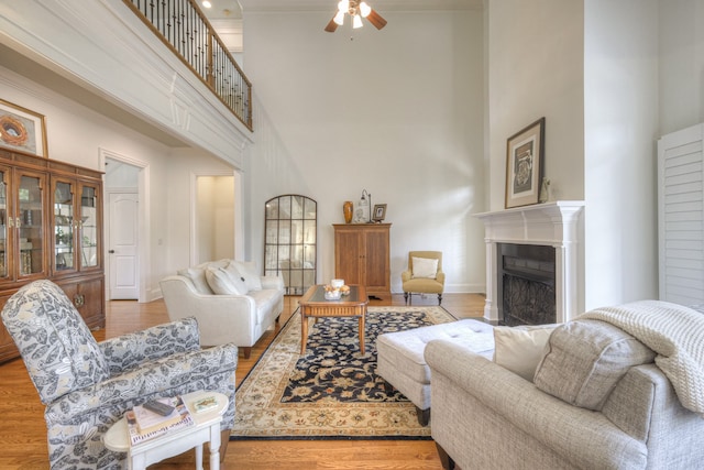 living room featuring a high ceiling, wood-type flooring, and ceiling fan