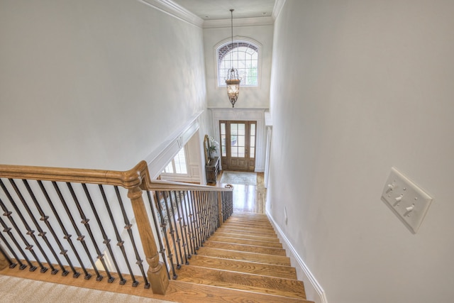 stairway with crown molding, a chandelier, and a healthy amount of sunlight