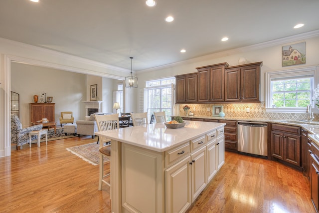 kitchen with pendant lighting, sink, dishwasher, a kitchen bar, and a kitchen island