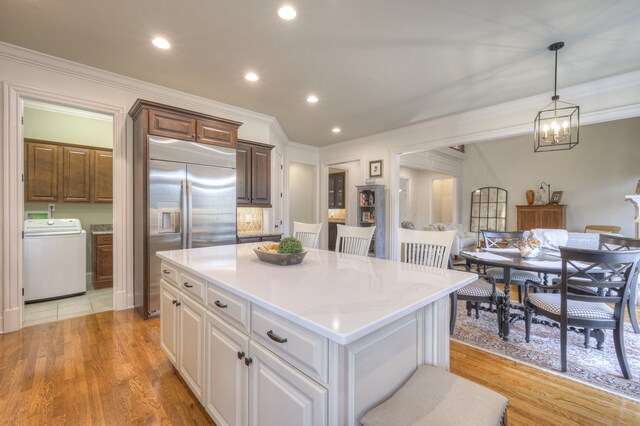 kitchen featuring pendant lighting, washer / clothes dryer, a center island, and white cabinets