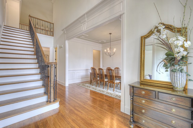 staircase with an inviting chandelier, hardwood / wood-style flooring, and ornamental molding