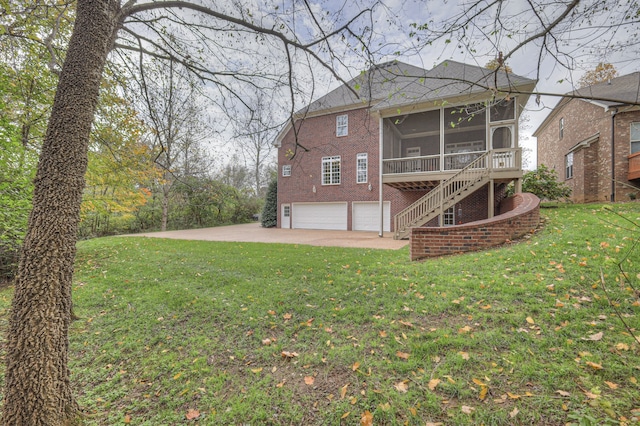 rear view of property featuring a garage, a sunroom, and a lawn