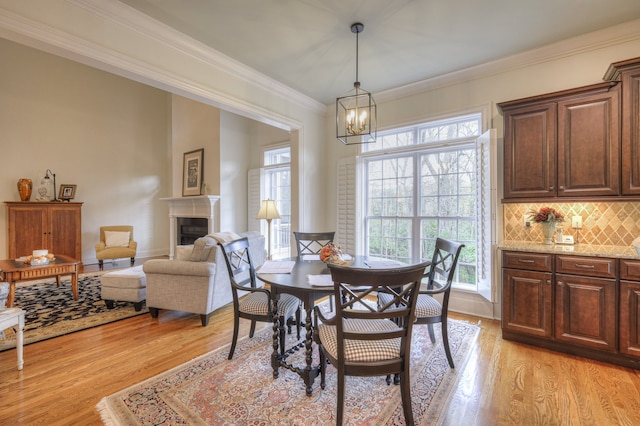 dining area featuring crown molding, an inviting chandelier, and light hardwood / wood-style floors