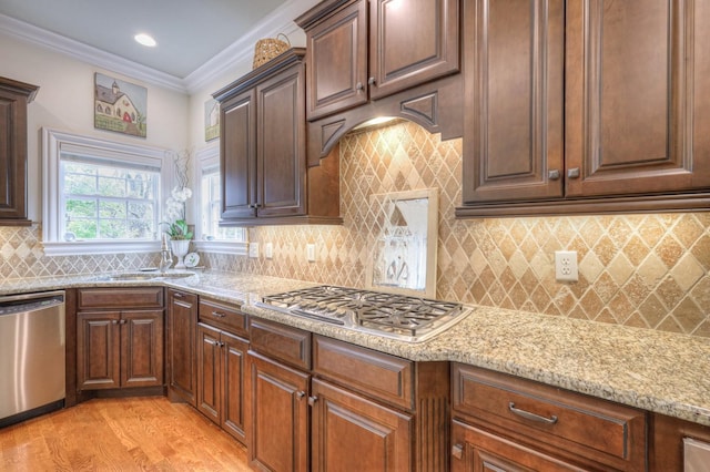 kitchen featuring sink, light hardwood / wood-style flooring, appliances with stainless steel finishes, light stone counters, and ornamental molding