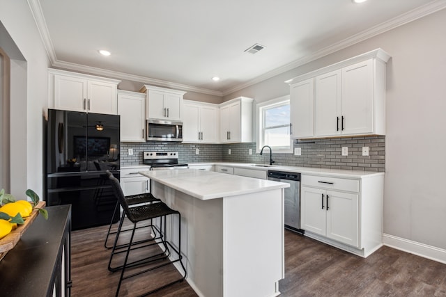 kitchen with white cabinets, dark hardwood / wood-style flooring, appliances with stainless steel finishes, and a center island