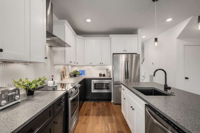 kitchen featuring white cabinets, wall chimney range hood, sink, light stone countertops, and appliances with stainless steel finishes