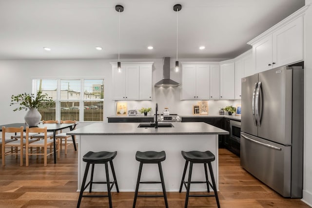 kitchen featuring dark hardwood / wood-style flooring, stainless steel fridge, sink, and wall chimney exhaust hood