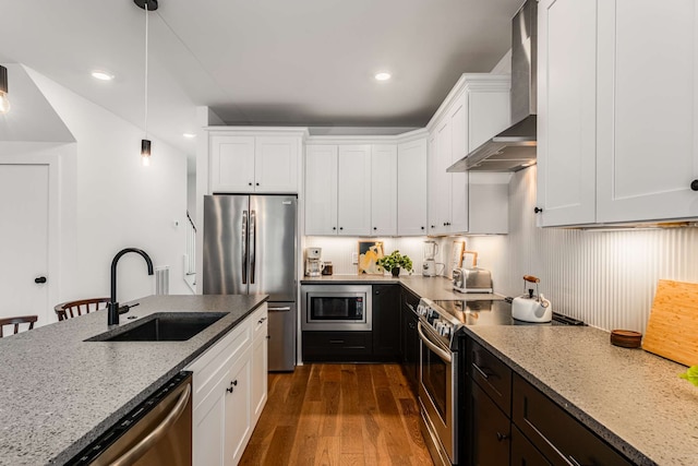 kitchen featuring sink, wall chimney exhaust hood, dark wood-type flooring, white cabinets, and appliances with stainless steel finishes