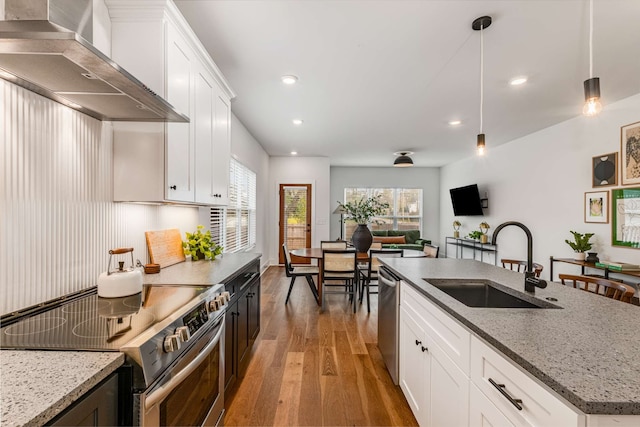 kitchen featuring white cabinetry, sink, hardwood / wood-style floors, pendant lighting, and appliances with stainless steel finishes