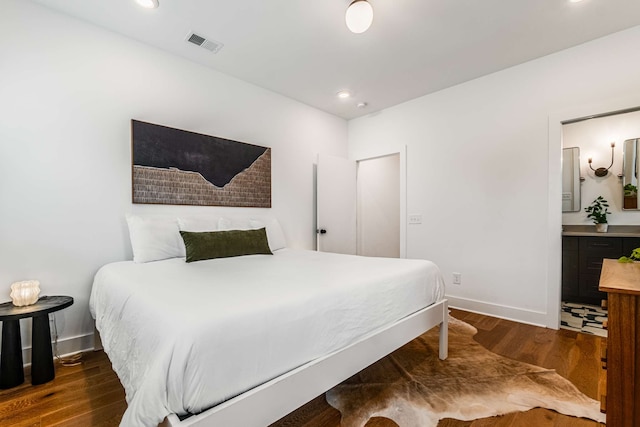 bedroom with ensuite bathroom and dark wood-type flooring