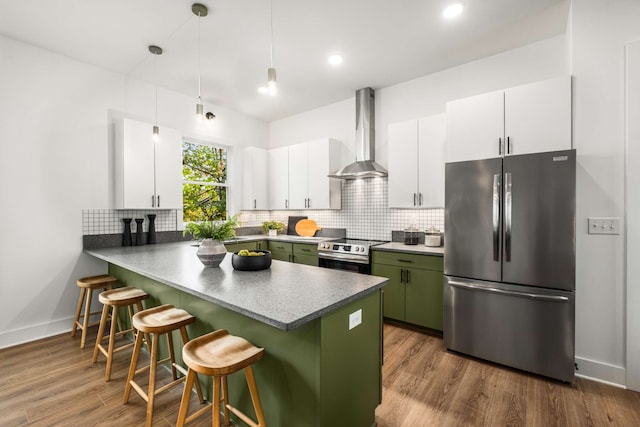 kitchen with white cabinets, green cabinets, wall chimney range hood, and stainless steel appliances