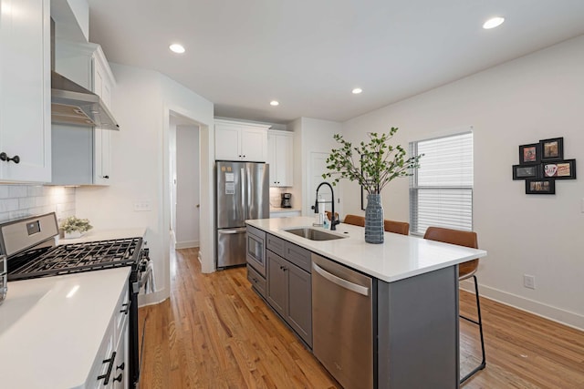 kitchen with white cabinets, sink, an island with sink, appliances with stainless steel finishes, and a breakfast bar area