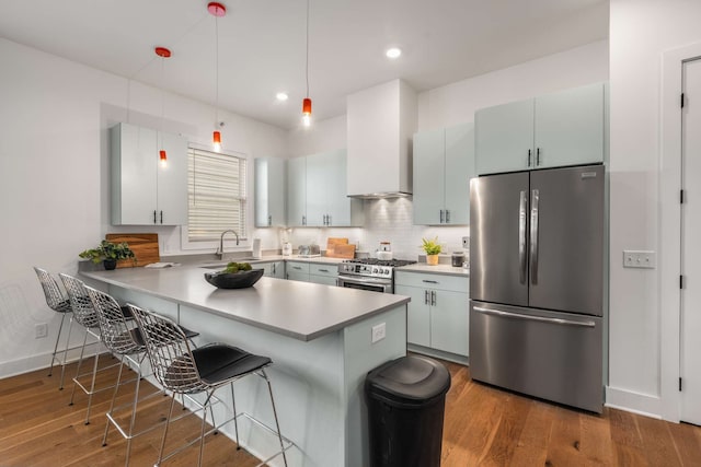 kitchen with pendant lighting, dark hardwood / wood-style floors, kitchen peninsula, and appliances with stainless steel finishes