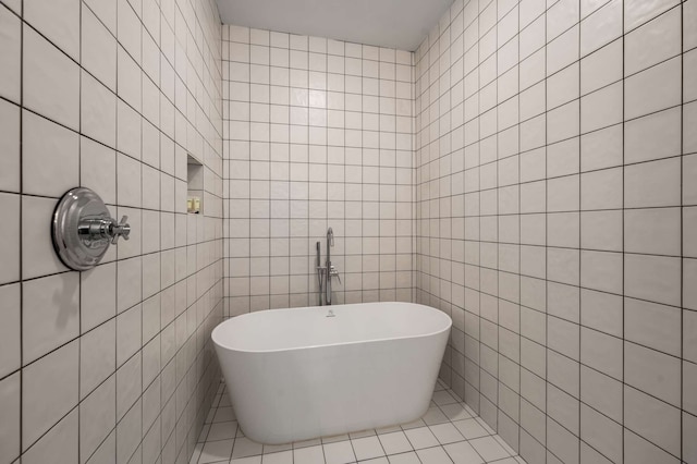 bathroom with tile patterned floors, a bathing tub, and tile walls