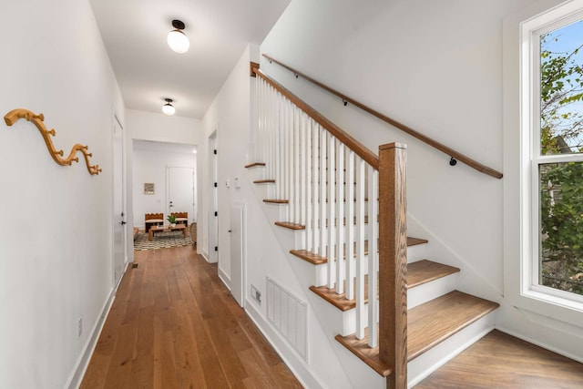 stairs featuring a wealth of natural light and hardwood / wood-style floors