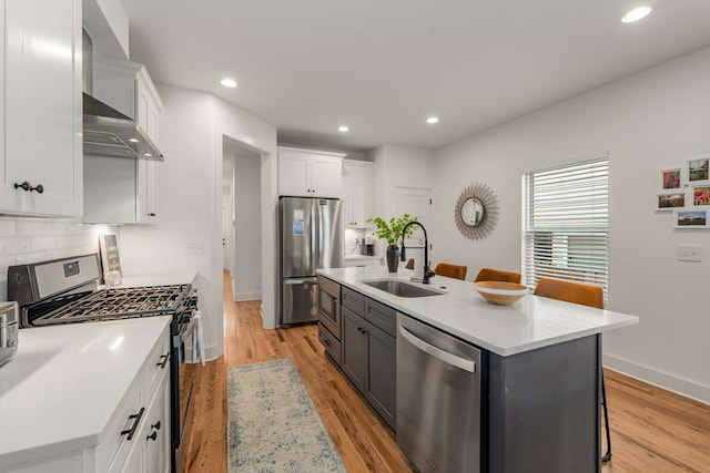 kitchen featuring sink, a kitchen breakfast bar, a kitchen island with sink, white cabinets, and appliances with stainless steel finishes