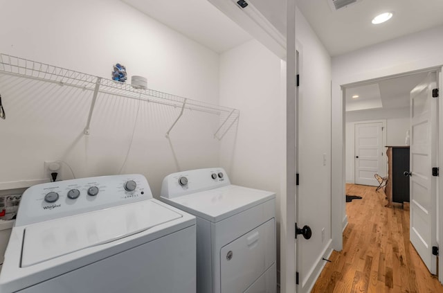 laundry room with washer and clothes dryer and light wood-type flooring