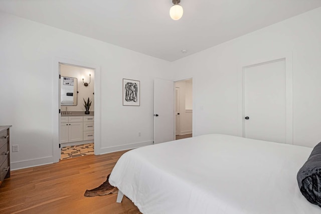 bedroom featuring light wood-type flooring and ensuite bath