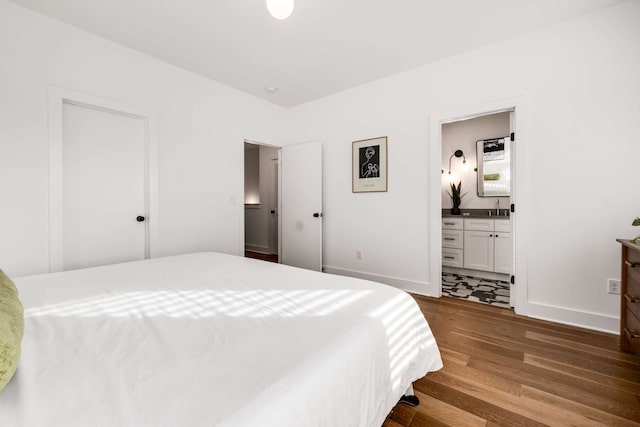 bedroom with ensuite bathroom, hardwood / wood-style flooring, and sink