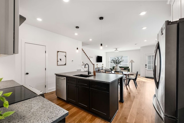 kitchen with sink, a center island with sink, light hardwood / wood-style floors, and appliances with stainless steel finishes