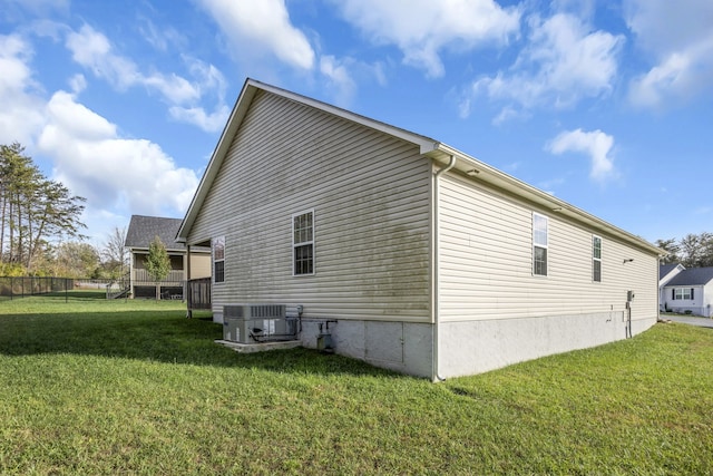 view of side of property featuring cooling unit and a yard