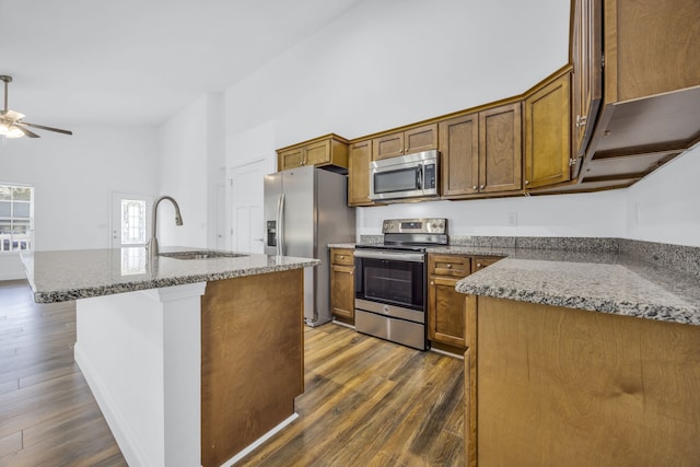 kitchen featuring dark wood-type flooring, sink, a kitchen island with sink, and appliances with stainless steel finishes