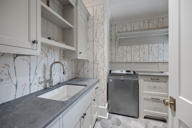 kitchen with white cabinets, washer / dryer, sink, and crown molding