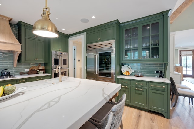 kitchen featuring green cabinetry, appliances with stainless steel finishes, decorative light fixtures, and backsplash