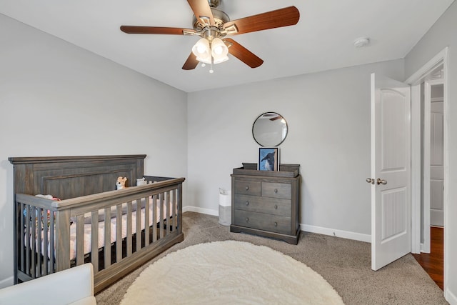 bedroom with ceiling fan, a nursery area, and carpet floors