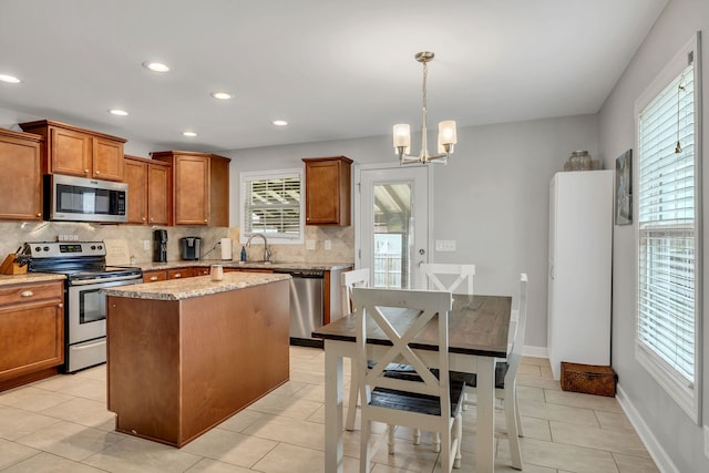 kitchen with stainless steel appliances, a center island, a chandelier, tasteful backsplash, and pendant lighting