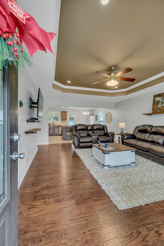 living room featuring dark hardwood / wood-style floors, ceiling fan, and a tray ceiling