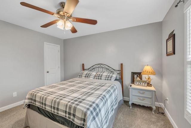 bedroom featuring ceiling fan, multiple windows, and light colored carpet