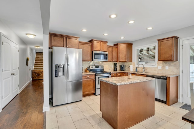 kitchen featuring stainless steel appliances, sink, tasteful backsplash, a kitchen island, and light hardwood / wood-style flooring